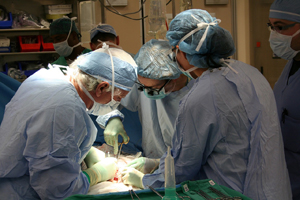 three surgeons operating on a patient