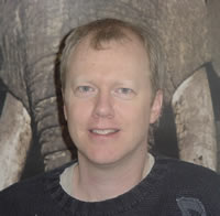 photo of Terrill Thompson  standing casually before a backdrop of a raging elephant
